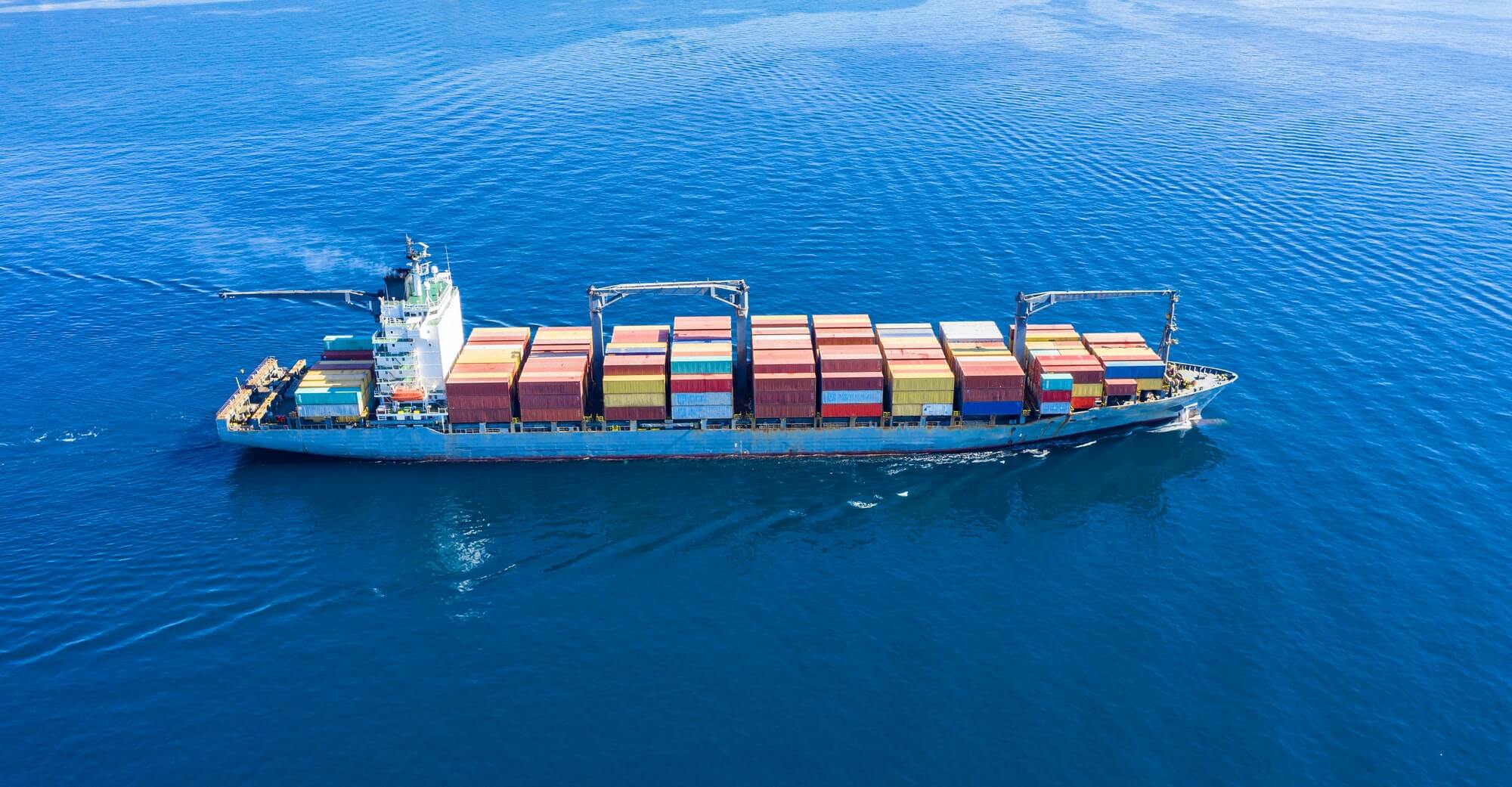 cargo-ship-full-loaded-with-containers-blue-sea-background